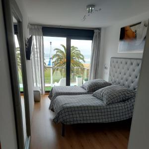 a bedroom with two beds and a large window at Apto playa Alojamientos Marte in Suances