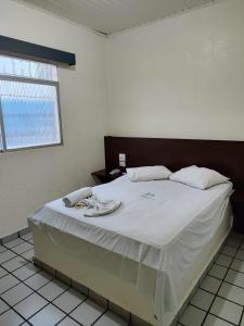 een slaapkamer met een groot bed met witte lakens bij Hotel Amazonia in Castanhal
