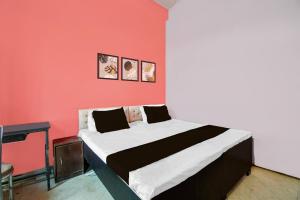 a bed in a room with a red wall at Hotel O Happy Inn in Gorakhpur +21 photos