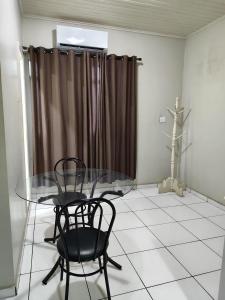 een eetkamer met een glazen tafel en 2 stoelen bij Hotel Amazonia in Castanhal