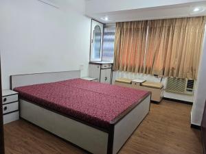 a bedroom with a large bed with a purple comforter at Mumbai Properties in Mumbai