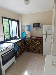 una cocina con fregadero y refrigerador en Apartamento Prainha perto de tudo pe na areia - 3 andar escada, en Caraguatatuba