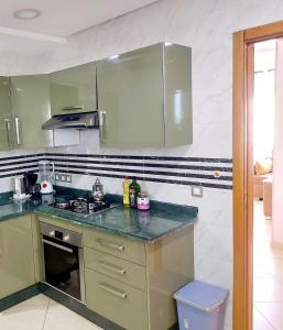 a kitchen with green cabinets and a counter top at Grand Appartement Idéal - Plein Coeur de Kénitra in Kenitra