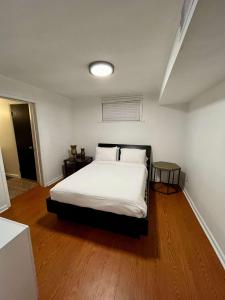 a bedroom with a bed with white sheets and wooden floors at Lafayette House-5 BR Garden Kitchen & Free Parking in Lafayette