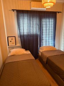 two beds in a small room with a window at 2 Bedroom 2 Bath Modern Apartment in Athens