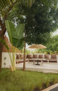 Lush Life - Private Bali-Inspired Villa في Kanāria: فناء فيه كراسي ومظلة واشجار