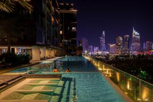 a infinity pool with a city skyline at night at Lè Métropole Saigon in Ho Chi Minh City