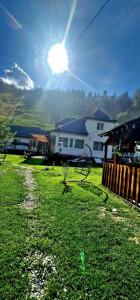 a house in a yard with the sun in the sky at Casa cu Bujori in Moieciu de Sus
