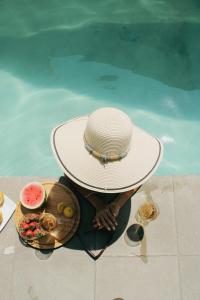 a person wearing a hat sitting next to a swimming pool at Casa Calec 2BR Apartment with Pool & Terrace in Manzanillo
