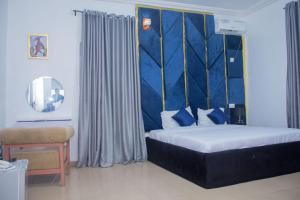un dormitorio con una cama con cabecero azul en Montevar Hotel, en Benin City