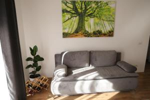 a couch in a living room with a tree painting on the wall at Hushu Apartment in Giroc +16 photos