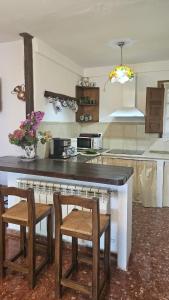 a kitchen with a counter with two chairs and a table at Casa Rural La Chaparra - Apartamento Fondales in Pitres