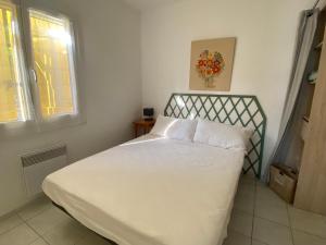 a bedroom with a bed with white sheets and a window at Les gîtes de Pailhès in Pailhès