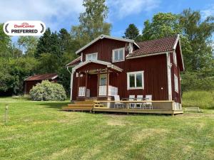 a red house with a large porch on a yard at 8 person holiday home in ANNEBY-By Traum in Aneby