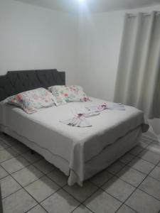 a bed with a white blanket and pillows on it at No jardim in Pomerode