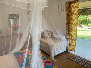 a bedroom with a bed with mosquito nets at Teumuhonu Tikehau in Tikehau