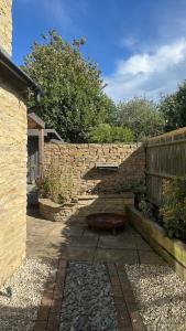 a stone wall with a bench in a courtyard at Entire Cotswolds barn retreat in Carterton