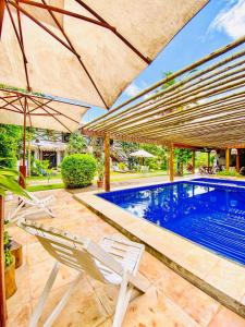 a swimming pool with two chairs and an umbrella at Bougainville Icaraí de Amontada in Amontada