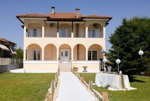 Una gran casa blanca con una mesa delante de ella. en Casa Verde Trikala, en Tríkala