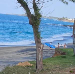 a group of people walking on the beach with a surfboard at Villa Molina Del Mar in Arecibo