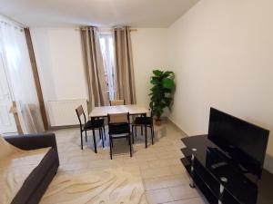 a living room with a table and chairs and a television at Le Refuge Nature à 20 min de Paris et d'Orly via RER Juvisy in Draveil