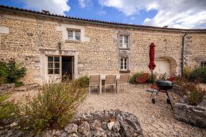 a brick building with a table and chairs and a grill at Logis du paradis in Criteuil-la-Magdeleine