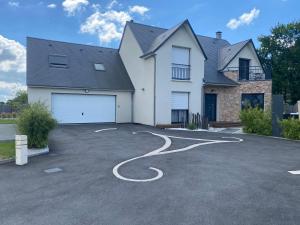 a house with a driveway with a white garage at L'Eden de la Guyonnière in Ruaudin
