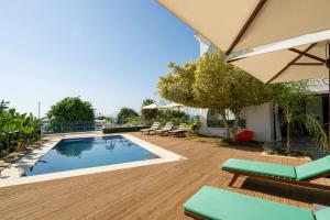 a pool with chairs and an umbrella on a wooden deck at Dar Elyssa in Sidi Bou Saïd