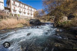a river with rapids in front of a building at Mulhacen Apartment in Trevélez