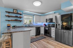 a kitchen with white cabinets and black appliances at Pirate's Cove Bungalow in Conway