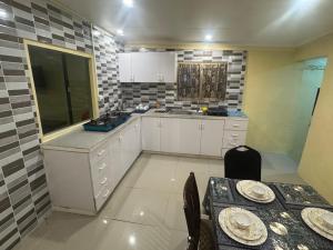 a kitchen with white cabinets and a table with plates on it at VULA Bnb in Suva