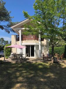 a building with a picnic table and a pink umbrella at VILLA LACANAU OCÉAN DANS LE GOLF in Lacanau-Océan