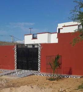 un edificio rojo y blanco con una puerta negra en Villa Shérazade, en Saint-Louis