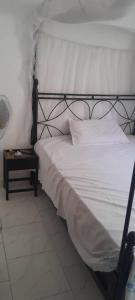 una cama con marco negro y sábanas blancas en Villa Shérazade, en Saint-Louis