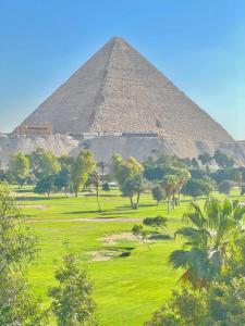 une pyramide dans un champ avec des arbres devant elle dans l'établissement Moonlight golf view, au Caire
