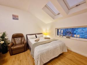 a bedroom with a bed and a chair and a window at Neue Moderne FeWo Europa-Park & Rulantica in Ringsheim