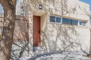 a white building with a red door and a tree at Las Tipas mini loft Cafayate in Cafayate