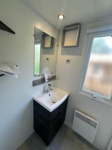 a bathroom with a sink and a mirror and a window at Bungalow 87, 8 personnes Camping Siblu Le Lac des Reves in Lattes