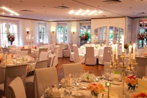 um salão de banquetes com mesas brancas e cadeiras brancas em Waldhaus an de Miälkwellen em Ladbergen