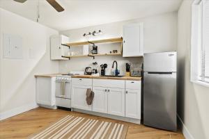 Una cocina con gabinetes blancos y un refrigerador de acero inoxidable. en King Bed Modern Studio Apartment, en Huntsville