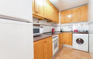 a kitchen with wooden cabinets and a washer and dryer at Awesome Apartment In Torrevieja With Wifi in Torrevieja