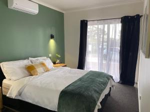une chambre avec un grand lit et une fenêtre dans l'établissement Serenity Cottage Wonthaggi, à North Wonthaggi