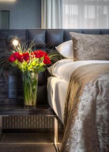 a vase of red flowers on a table next to two beds at Hotel Mucha in Prague