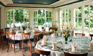 ein Esszimmer mit Tischen und Stühlen und Fenstern in der Unterkunft Waldhaus an de Miälkwellen in Ladbergen