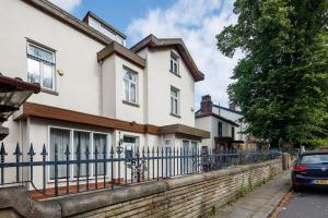 a house with a fence and a car parked in front at Beautiful 'Mayfield' Villa with private pool! in Manchester