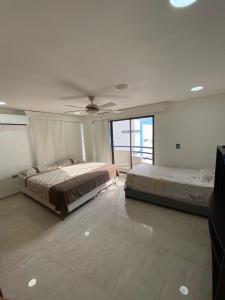 une chambre avec deux lits et un ventilateur de plafond dans l'établissement APTO DUPLEX MARINA DEL REY CARTAGENA, à Carthagène des Indes