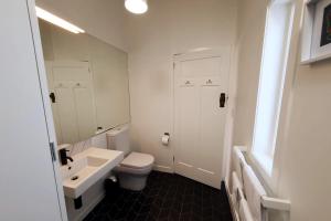 a bathroom with a white toilet and a sink at The Cottage on the Olive Grove in Russell +15 photos