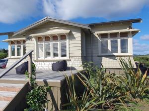 a small white house with a wooden deck at The Cottage on the Olive Grove in Russell
