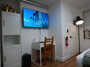 a room with a desk and a tv on a wall at 10 Minute walk to Light Rail in Jersey City