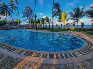 a pool with palm trees and the ocean in the background at Spacious Penthouse with Stunning Beachfront Views 2 in Mombasa